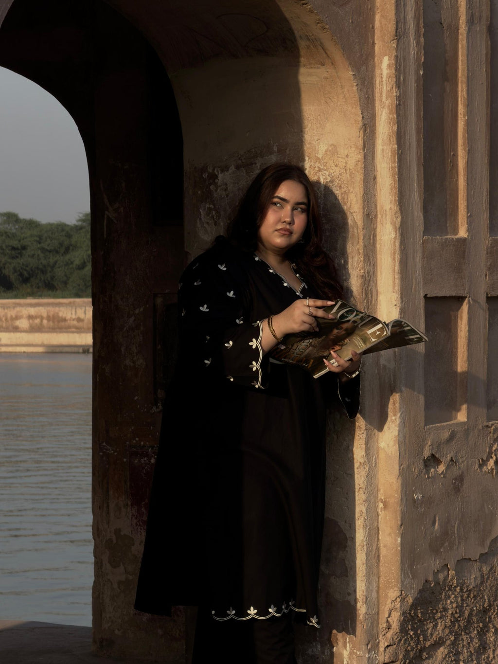 Model wearing the Black Embroidered kurta set with ivory floral embroidery, standing in a Mughal archway